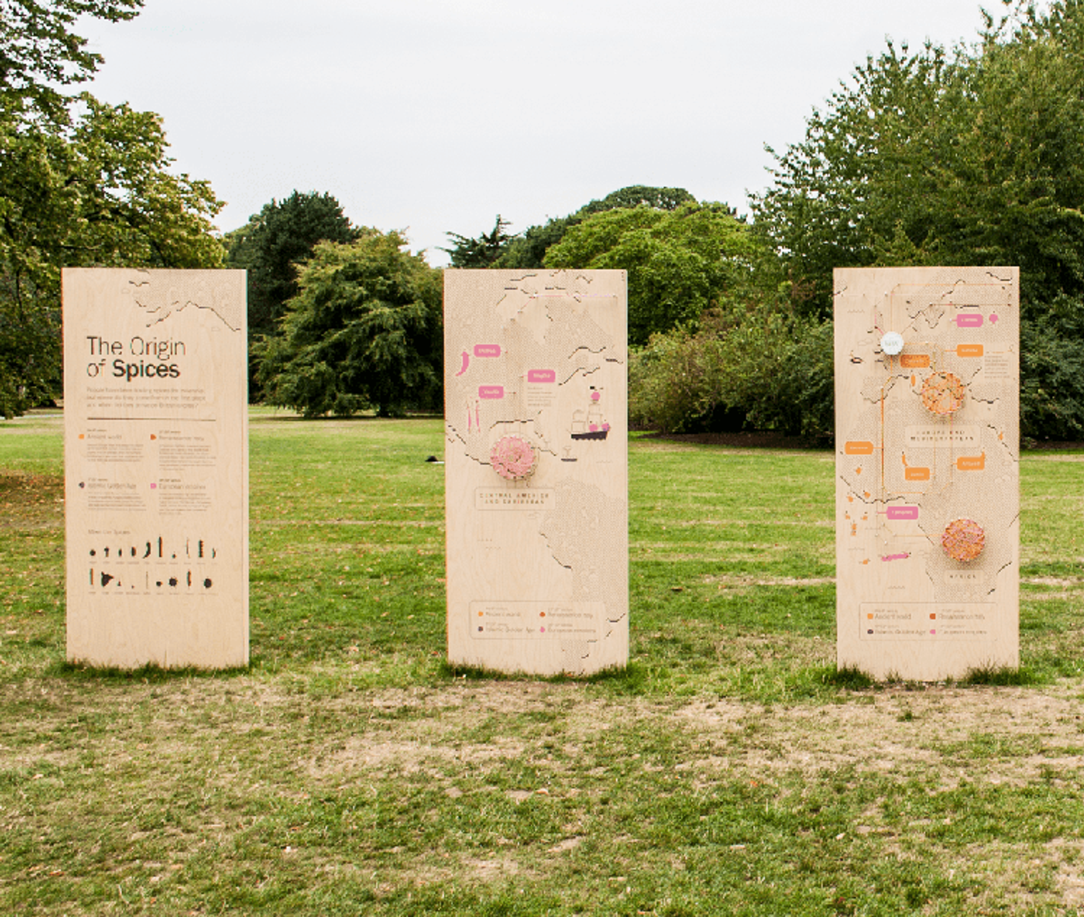 A photo of three wooden monoliths showing the origin of spices map as they were displayed outdoors at Kew Gardens.